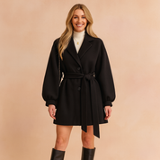 Elegant black belted wool coat with balloon sleeves, paired with a white turtleneck sweater and knee-high black boots, showcasing a chic and sophisticated winter style.