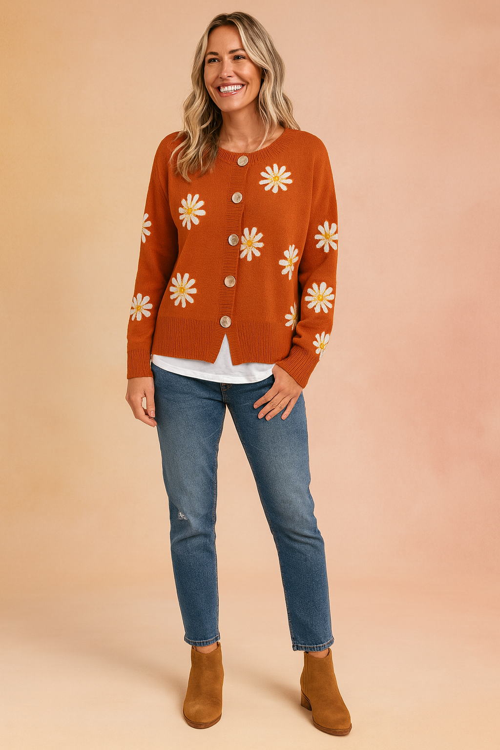 Orange button-up cardigan with white daisy prints, paired with a white undershirt, blue jeans, and tan ankle boots.