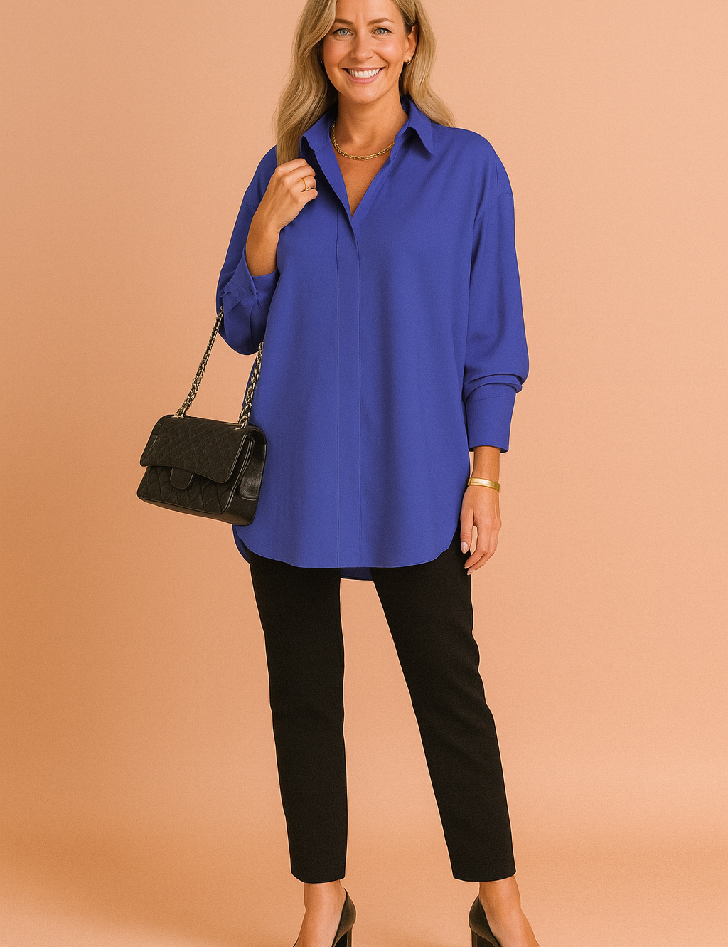 Royal blue oversized long-sleeve blouse with a clean collar and concealed front placket, paired with slim black trousers and classic black block-heeled pumps; accessorized with a quilted black handbag.