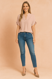 Women's casual outfit featuring a short-sleeve emerald green V-neck blouse paired with high-rise blue skinny jeans.