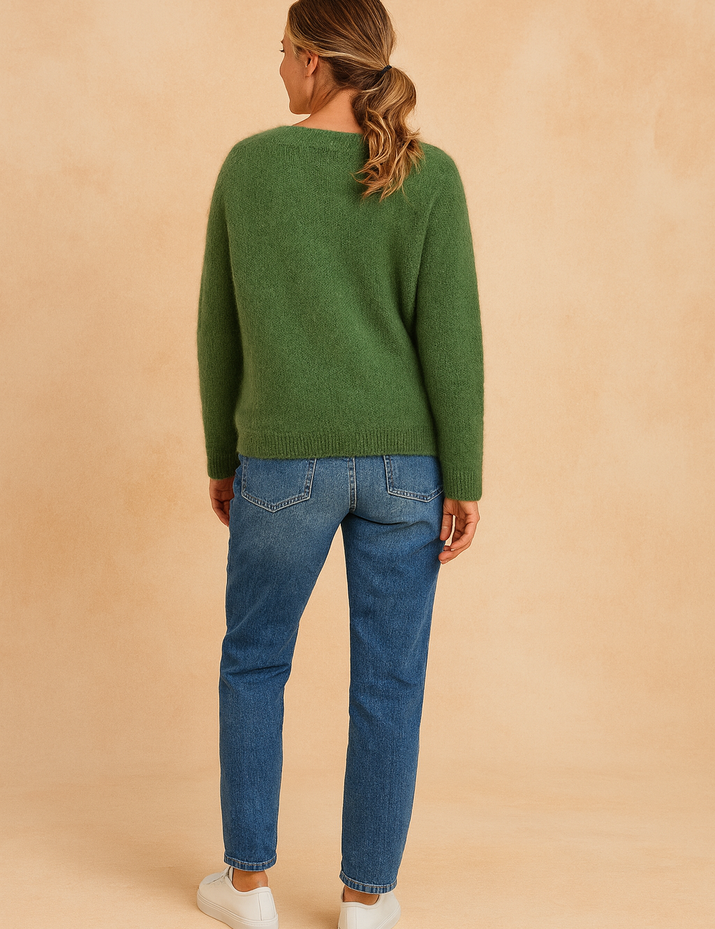 Back view of a forest green fuzzy knit sweater with a plain design, paired with mid-rise straight-leg blue jeans and white low-top sneakers.