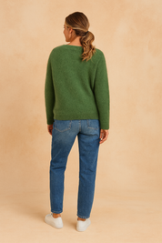 Back view of a forest green fuzzy knit sweater with a plain design, paired with mid-rise straight-leg blue jeans and white low-top sneakers.