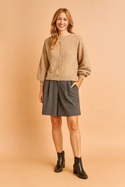 Beige button-up cardigan with long sleeves paired with charcoal gray A-line shorts and black leather ankle boots.