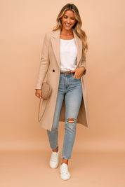 Beige longline wool coat paired with a white pocket t-shirt, light wash ripped skinny jeans, white sneakers, and a quilted beige crossbody bag.