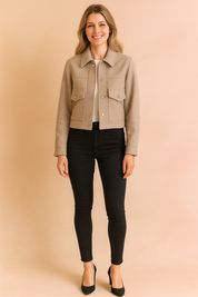 Cropped beige button-up jacket with flap chest pockets and a structured collar, paired with fitted black skinny jeans and black heels for a sleek modern look.