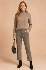 Beige high-neck knit sweater with long sleeves, paired with tailored plaid trousers in grey tones, styled with black ankle boots and a quilted leather handbag.