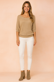 Beige textured knit sweater with a relaxed boat neckline, paired with slim-fit white jeans and taupe suede ankle boots.