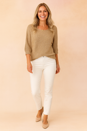 Light beige textured knit top with elbow-length sleeves paired with white slim-fit jeans and beige pointed-toe heels.