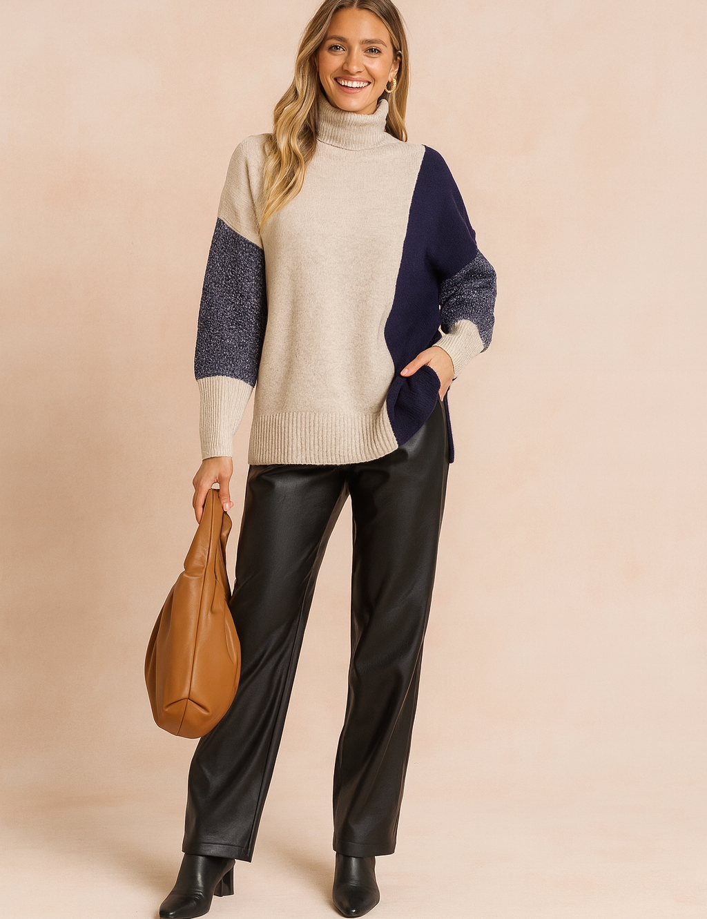Beige and navy colorblock knit turtleneck sweater with ribbed hem and cuffs, paired with black leather-look trousers and black ankle boots for a chic winter outfit.