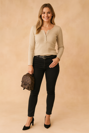 Beige ribbed long-sleeve Henley top with buttoned neckline, paired with high-rise black skinny jeans, a black belt, and a designer mini backpack.