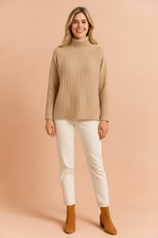 Beige ribbed high-neck knit sweater with long sleeves, featuring vertical and diagonal ribbed patterns, paired with off-white straight-leg pants and camel suede ankle boots.