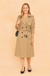 Classic beige trench coat with double-breasted button design, belted waist, epaulet shoulders, and mid-calf length, styled with a black handbag and black heels.