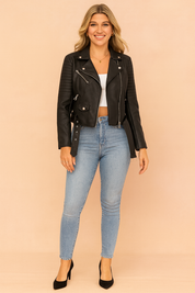 Black biker leather jacket with quilted shoulder panels, belted hem, zip pockets, and silver hardware, paired with light blue skinny jeans, a white cropped top, and black closed-toe heels.