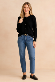 Black button-up cardigan with a round neckline, paired with classic blue straight-leg jeans, a black belt with gold buckle, and black leather loafers.