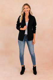 Black casual zipper jacket with long sleeves, flap chest pockets, button details, and a straight cut, styled with a white T-shirt and denim jeans.