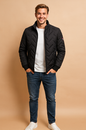 Black chevron quilted jacket with zip closure, side zip pockets, and sleeve patch detail styled for a modern casual look.