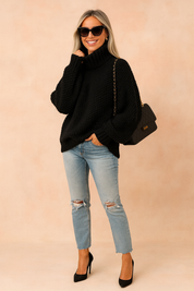  Oversized chunky-knit black turtleneck sweater paired with light-wash distressed straight-leg jeans, black pointed-toe high heels, and a black quilted chain-strap handbag.
