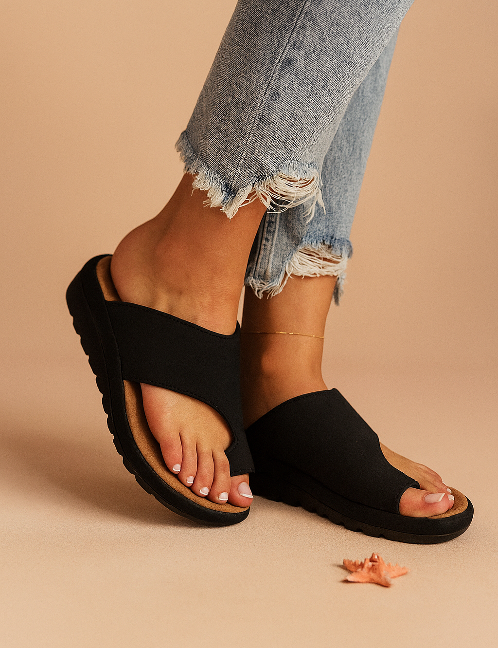Black cross-strap slide sandals with contoured tan footbeds and textured black outsoles, designed with an open-toe cut and casual ergonomic sole