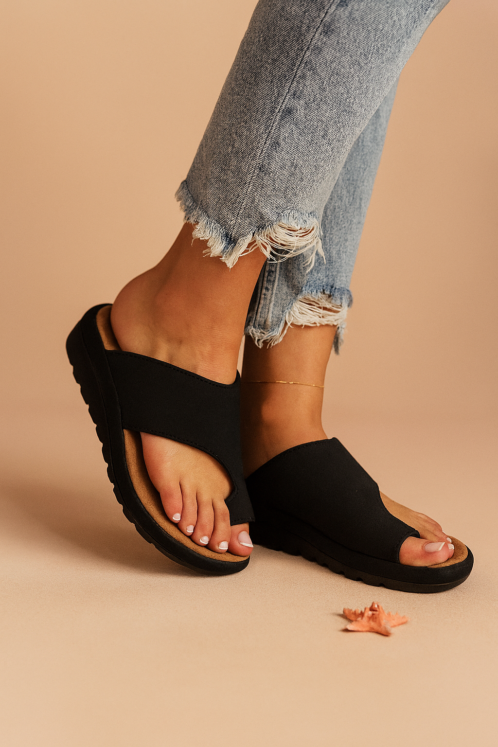 Black cross-strap slide sandals with contoured tan footbeds and textured black outsoles, designed with an open-toe cut and casual ergonomic sole
