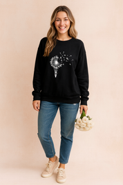 Black long-sleeve sweatshirt with white dandelion hot air balloon print, paired with blue jeans and beige sneakers, styled for casual wear.