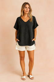 Relaxed black distressed linen blouse with subtle faded texture and rolled sleeves, styled with white linen shorts and white sandals, perfect for effortless summer fashion.