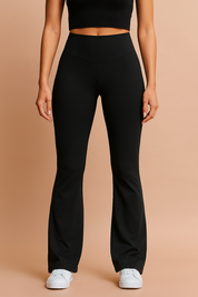 High-waisted black flared yoga pants with a smooth, seamless fit and slight stretch, paired with white sneakers for a clean athleisure look.