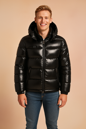 "Black glossy puffer jacket with hood, front zipper, zippered side pockets, and quilted padding, styled in a modern winter fashion look."
