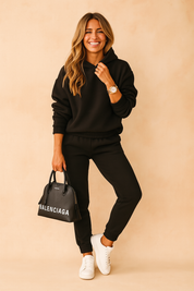 Black jogger hoodie lounge set with ribbed cuffs and waistband, styled with white sneakers and a black Balenciaga handbag.