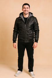 Black leather biker jacket with zip closure, multiple pockets, shoulder epaulets, and gray hood insert, styled with black trousers and gray sneakers.