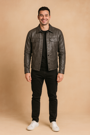 Black leather button-up jacket with flap chest pockets and sleek tailored fit, styled with black trousers and white sneakers.