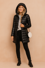 Black long winter puffer jacket with hood, quilted design, mid-thigh length, paired with black pants and lace-up ankle boots.