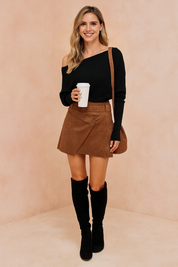 Black ribbed off-the-shoulder sweater paired with a brown suede wrap mini skirt and black knee-high suede boots.