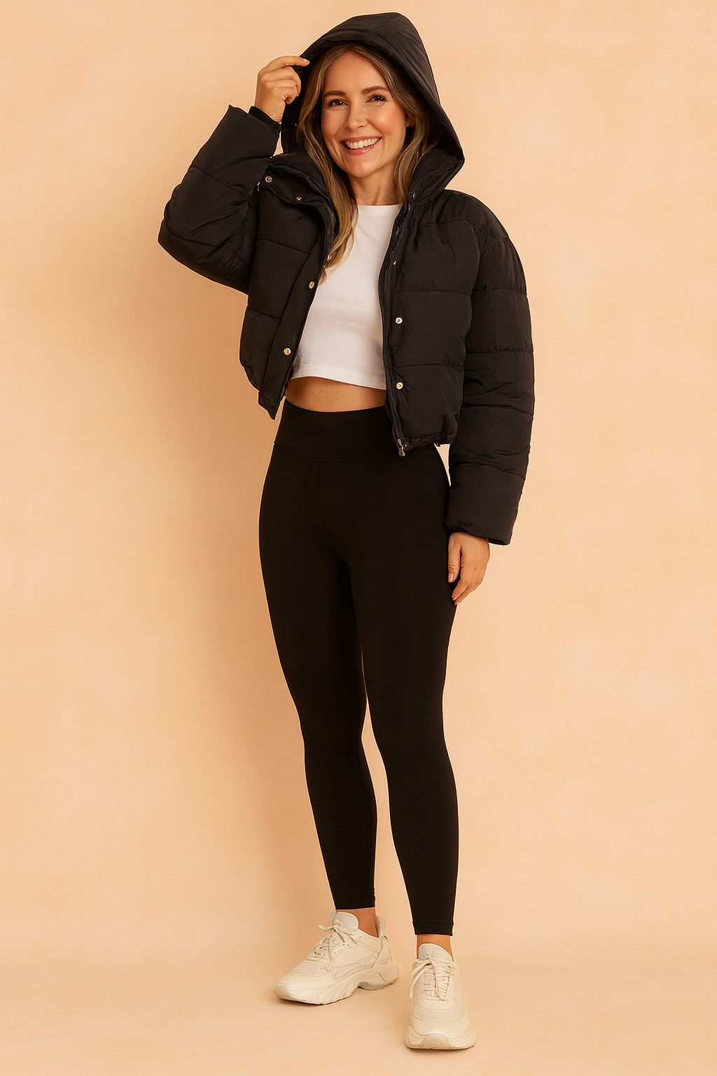 Black puffer jacket with front snap buttons, paired with a white cropped T-shirt, black high-waisted leggings, and chunky white sneakers.
