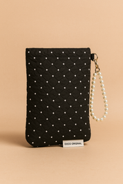 Upright black quilted pouch with delicate white pearl dots and a pearl bracelet strap, highlighted with a visible designer label and rich stitched texture.