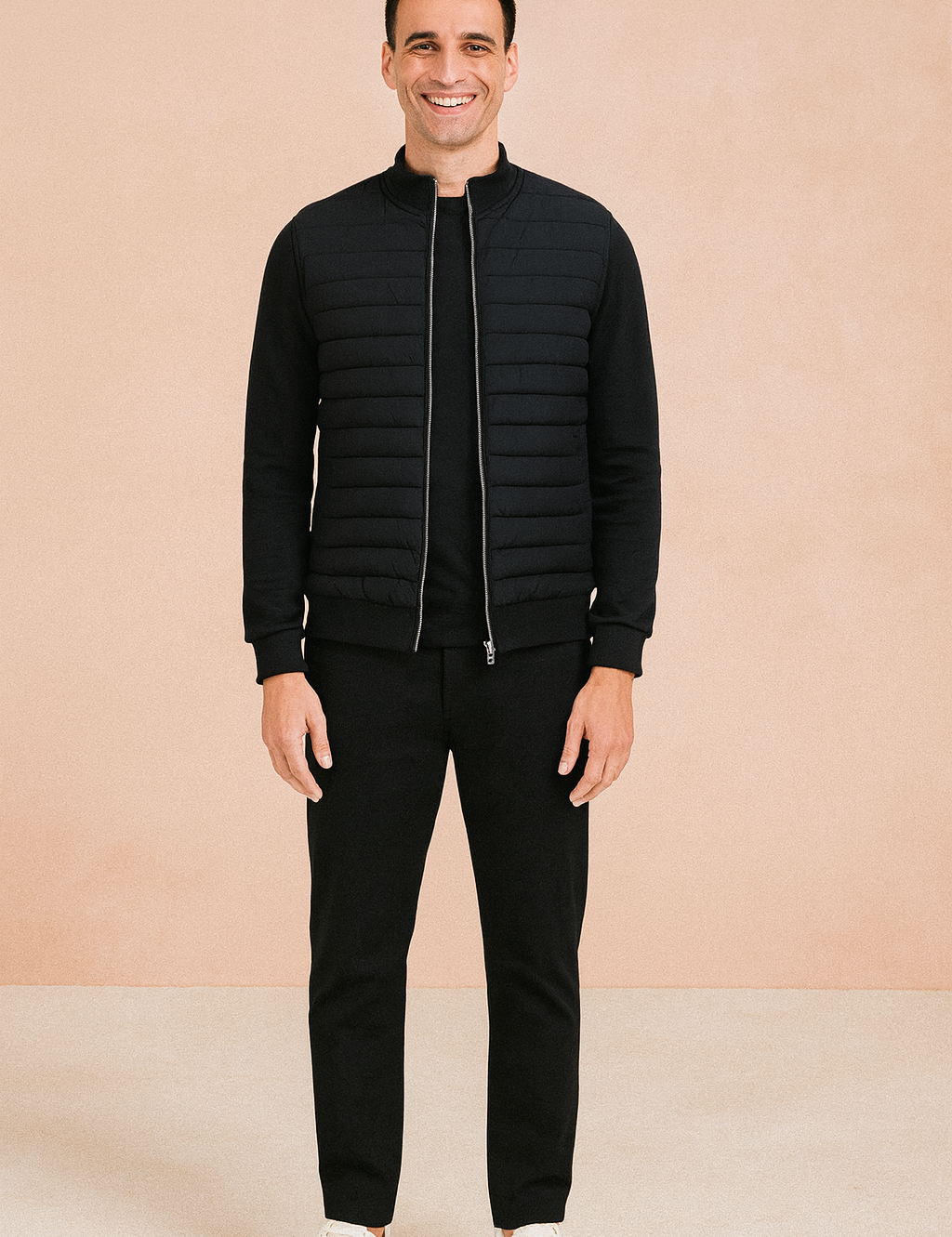 Black quilted zip-up jacket with ribbed cuffs and hem, styled with black trousers and white sneakers.