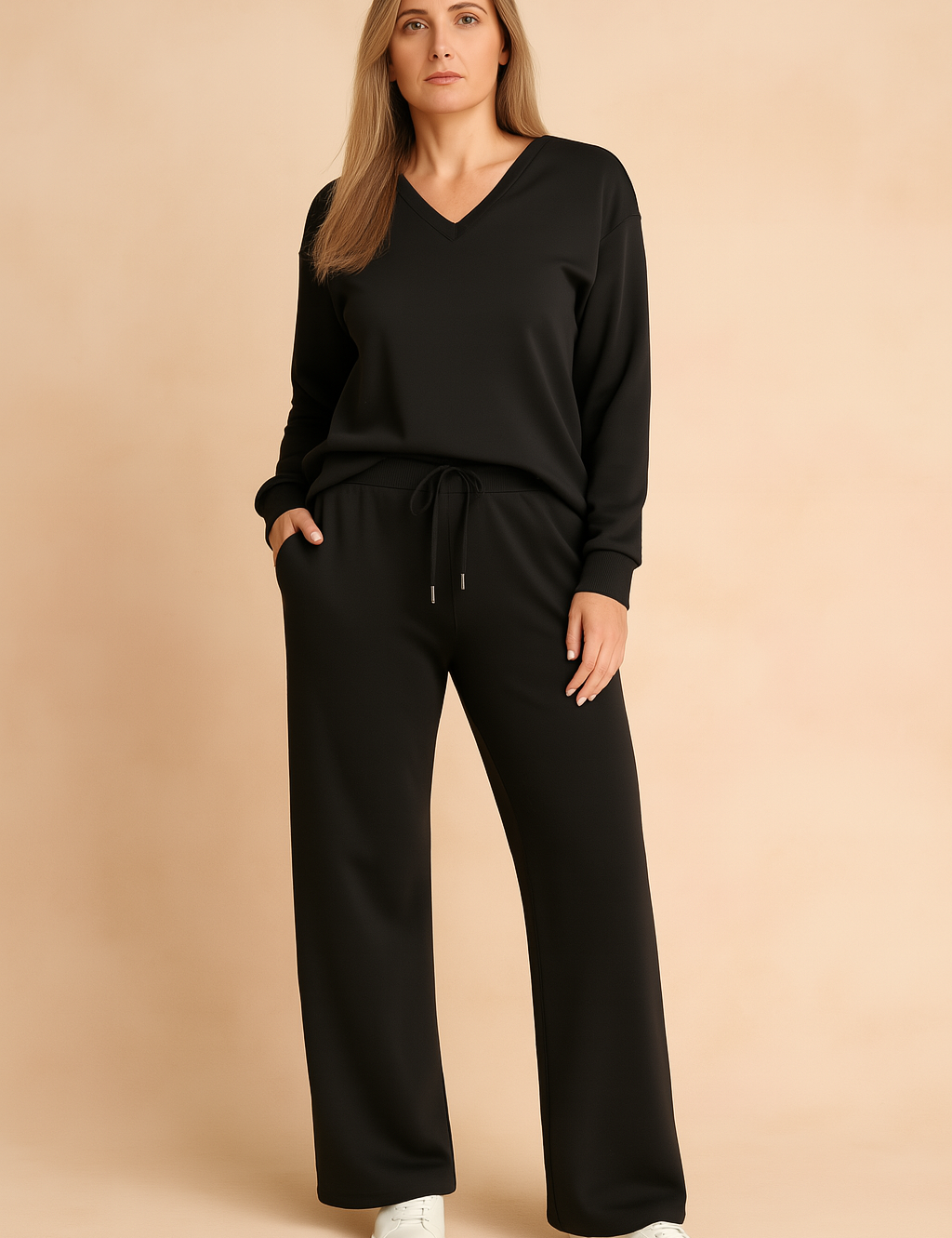 Black V-neck long-sleeve loungewear top with matching drawstring wide-leg pants, crafted from a smooth, relaxed-fit fabric, styled with white sneakers.
