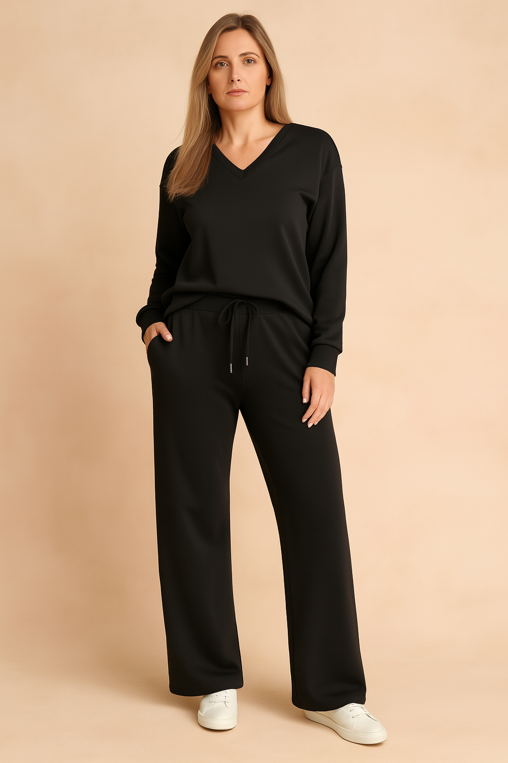 Black V-neck long-sleeve loungewear top with matching drawstring wide-leg pants, crafted from a smooth, relaxed-fit fabric, styled with white sneakers.