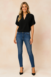 Women's casual outfit featuring a short-sleeve emerald green V-neck blouse paired with high-rise blue skinny jeans.