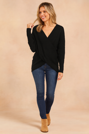 Black ribbed knit wrap sweater with an asymmetrical hem, paired with dark blue skinny jeans and tan ankle boots.