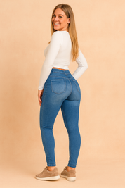 Light blue high-waisted skinny jeggings with faded wash details, paired with a fitted white crop top and taupe sneakers, styled in a clean pastel fashion shoot