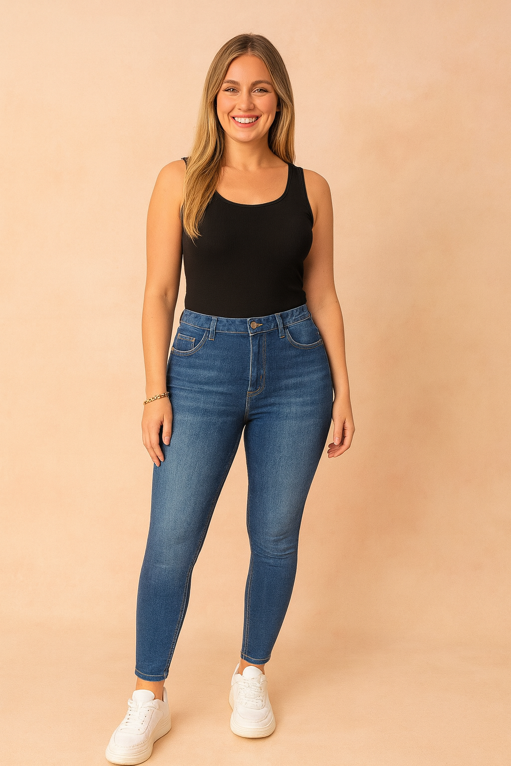 Blue high-waisted jeggings with faded wash styled with a black fitted tank top and white chunky sneakers, presented in a clean pastel fashion shoot