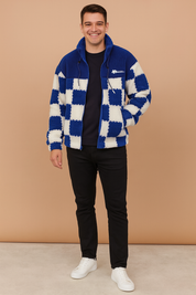 Blue and white checkerboard sherpa fleece zip-up jacket with drawstring collar, styled with black trousers and white sneakers.