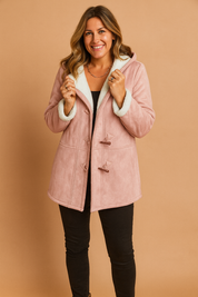 Blush pink faux suede toggle coat with white shearling lining, paired with a black top and black fitted pants.