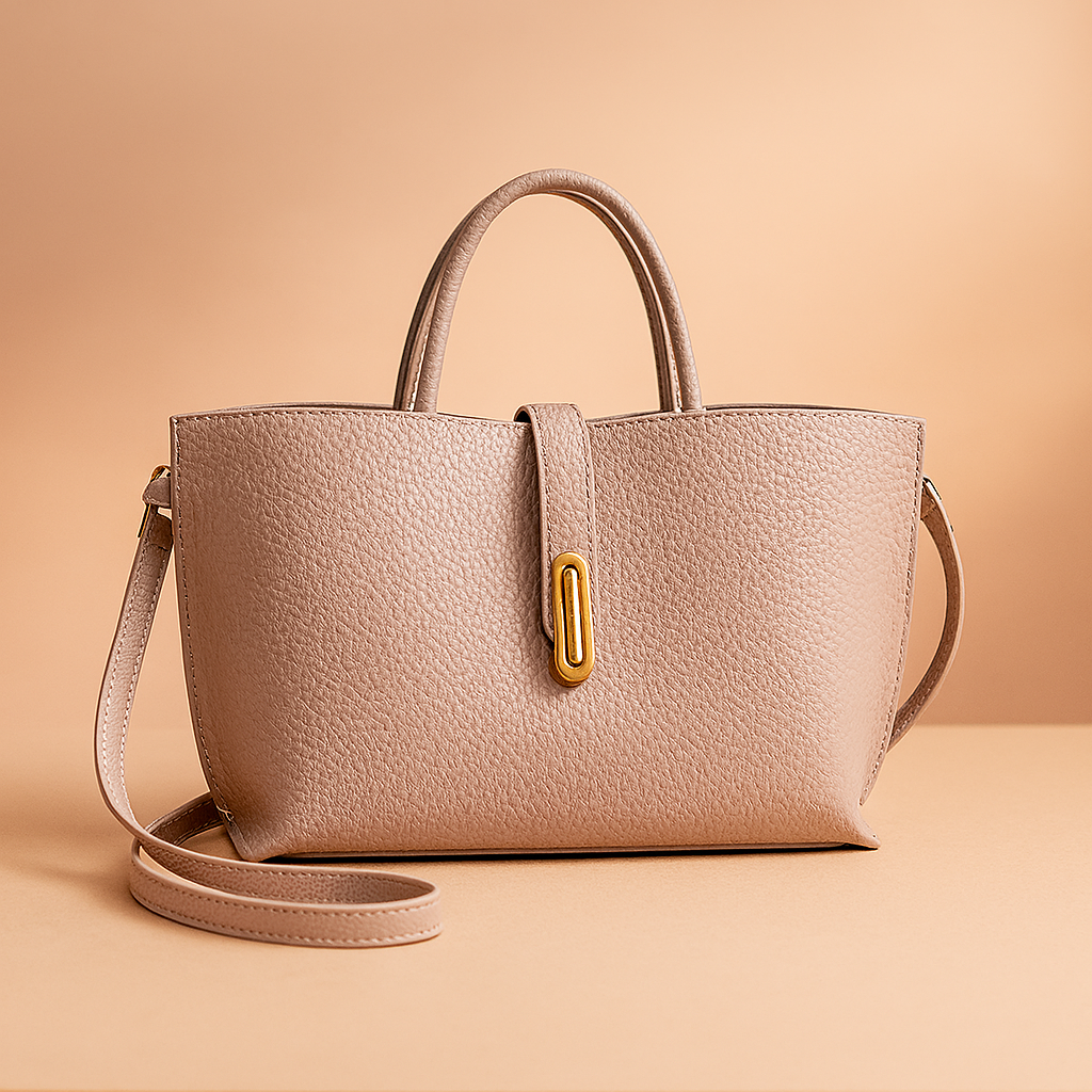 Blush taupe pebbled leather handbag with gold-tone clasp, curved handles, and matching shoulder strap.