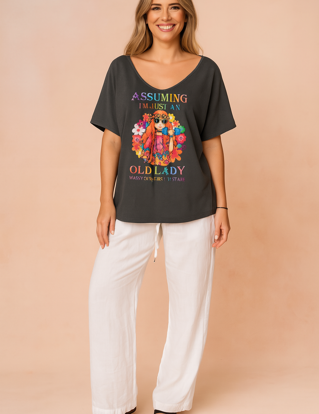 Dark gray oversized T-shirt with a colorful bohemian-style graphic and statement text, paired with loose white drawstring pants and black sandals for a relaxed, bold look.