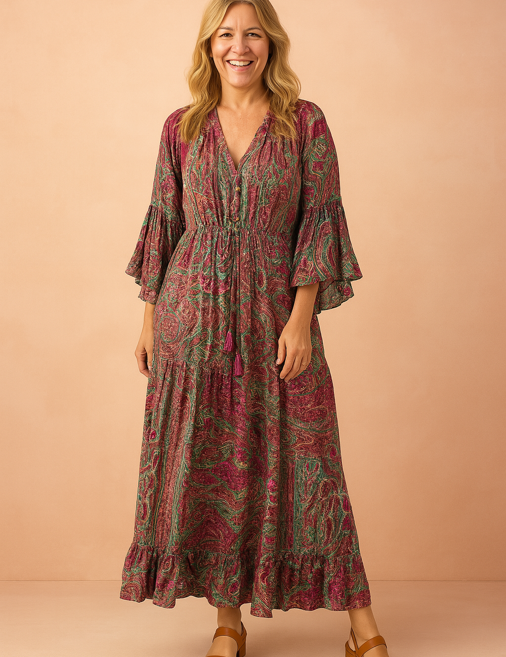 Bohemian paisley maxi dress featuring flared sleeves, a drawstring waist, and tiered hem, designed with vibrant magenta and green swirls in a textured print that remains true to the original pattern.