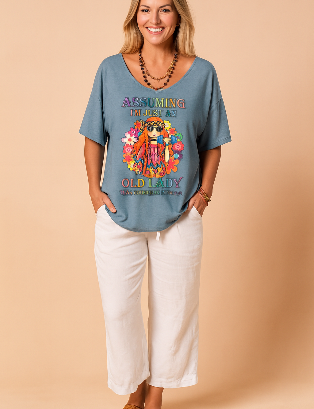 Loose-fit blue graphic T-shirt featuring a colorful boho print and bold lettering, paired with relaxed white linen pants and styled for casual summer wear.