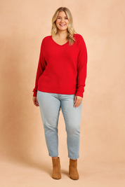 Bright red ribbed V-neck sweater paired with light-wash straight-leg jeans and tan suede ankle boots.