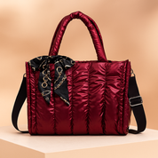 Metallic bronze quilted tote handbag with padded handles, black strap, and printed scarf detail on a neutral display.