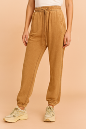 High-waisted brown corduroy jogger pants with elastic waistband, front pockets, adjustable drawstring, and gathered cuffs, styled with chunky sneakers for a casual streetwear look.